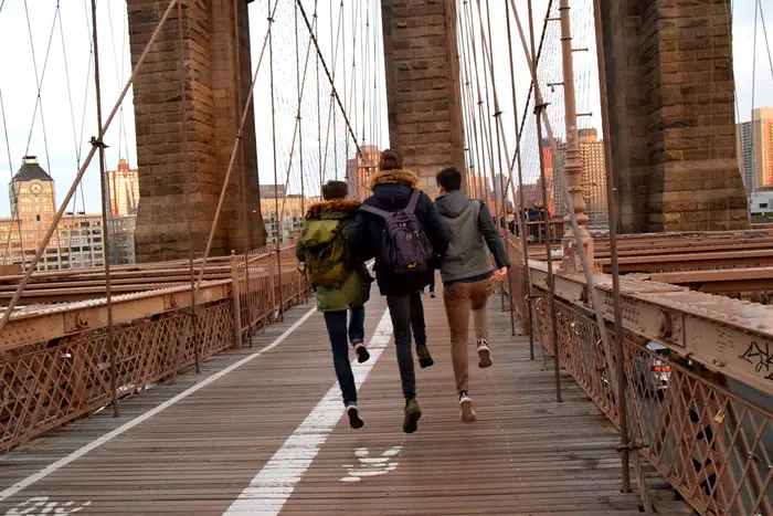 Three teens skip on the Brooklyn Bridge